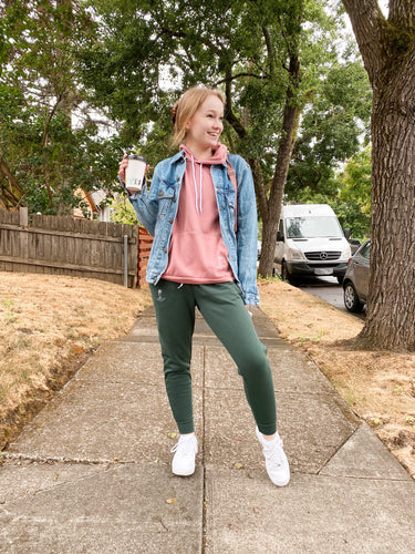 girl wearing emerald green sweatpants and a pink sweatshirt with a denim jacket. 