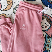 Load image into Gallery viewer, comfy pink sweatpants on soft blanket with angel logo 
