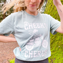 Load image into Gallery viewer, girl wearing light blue t shirt in the forest. The t shirt features a cherub riding a motorcycle and says &#39;The Cheeky Cherub&#39;
