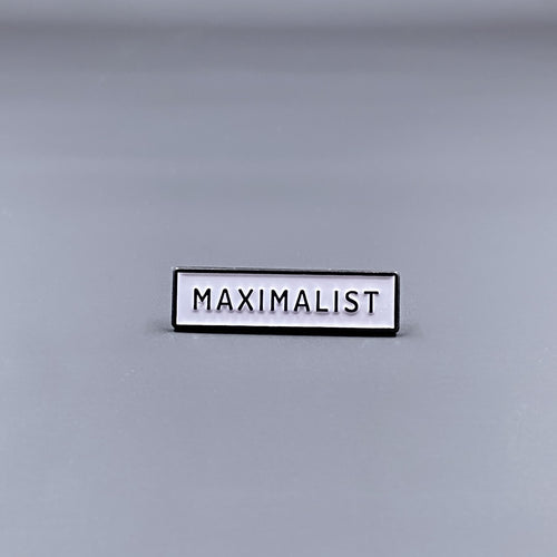 White Enamel Pin with the word 'Maximalist' written in black letters