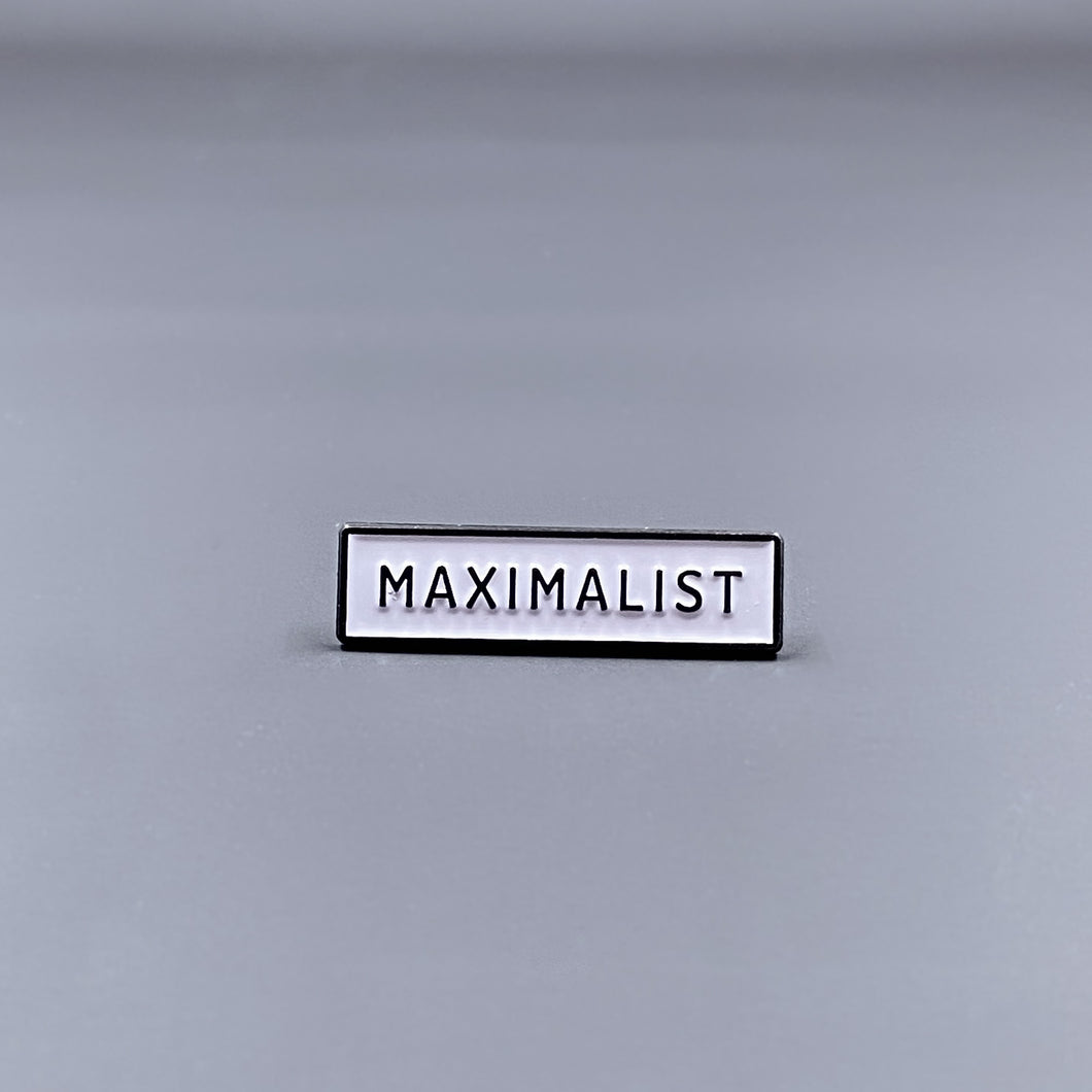 White Enamel Pin with the word 'Maximalist' written in black letters